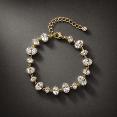 One wrist-worn chain bracelet. Gold-toned metal with polished finish; single flexible strand. Construction is a stone station chain: clear faceted elements in gold-tone prong cups, joined by small metal rings, plus a finer oval/curb-link extender. The main stone-bearing run is approximately 18–20 times the width of the largest oval station; the extender is about one-quarter of the main chain length. A working lobster-type clasp is visible.