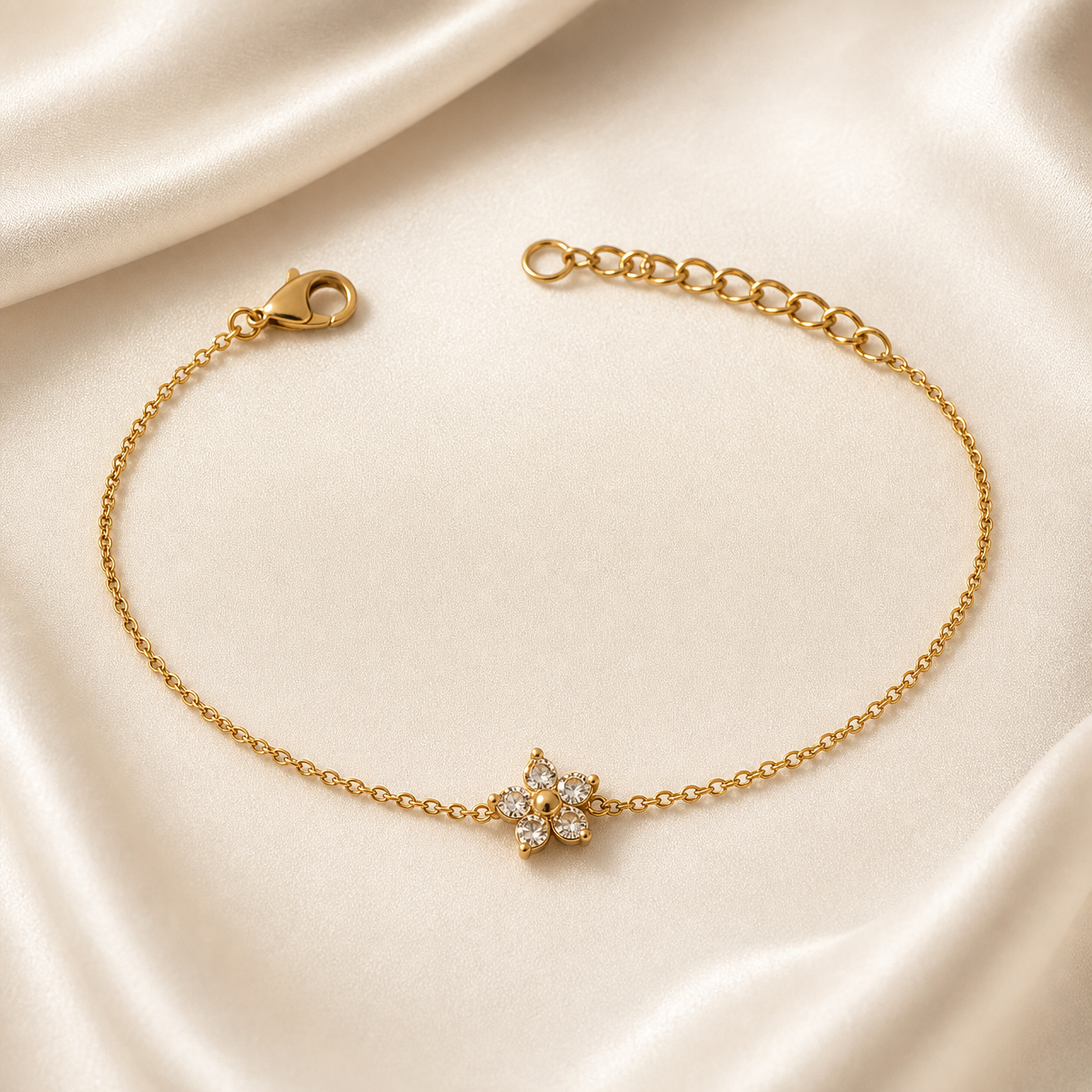 A single flexible bracelet or anklet in yellow-gold-toned metal with a polished finish. Construction is one continuous fine-gauge cable chain of small oval links. Starting from the clasp end: a lobster clasp attaches to the chain, followed by a long plain run of chain leading to the single decorative component, a small flower-shaped motif fixed between the two chain runs.