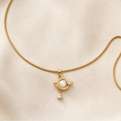 One necklace in yellow-gold-tone metal with a polished finish. It is a single-strand, fine-gauge snake chain terminating at one end in a lobster clasp and at the other in a short cable-link extender chain ending in a single flat oval terminal tag. From the clasp end along the strand there are no stations or beads until the far end, where one pendant hangs from a fixed bail.
