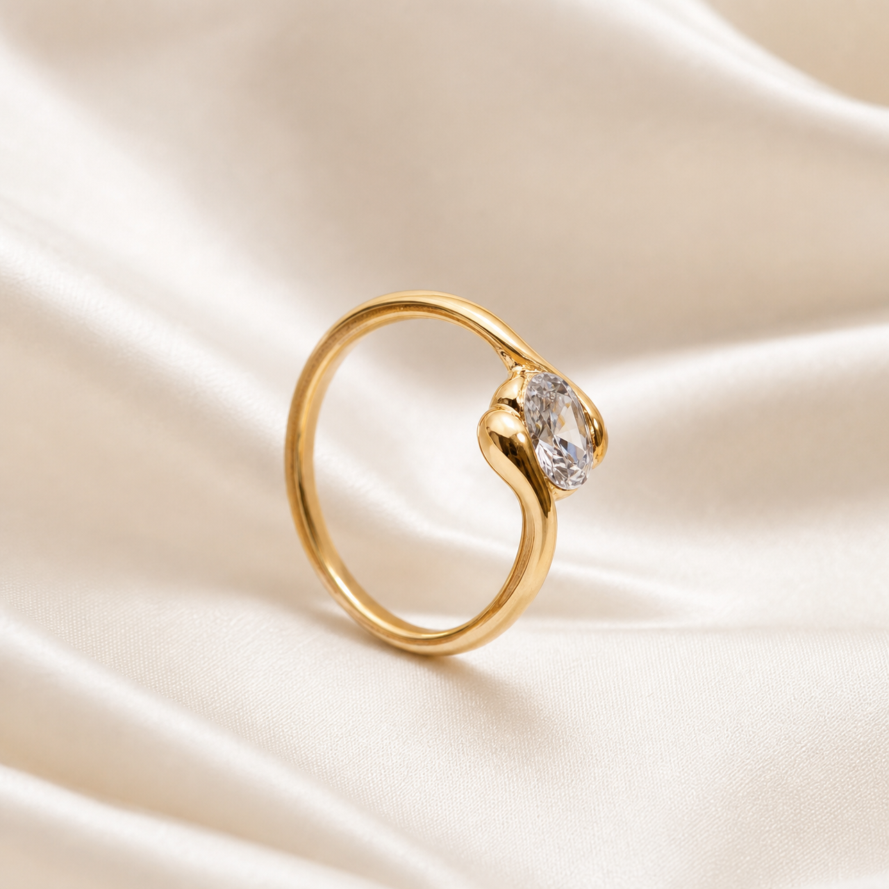 One ring. Yellow-gold-coloured metal with a polished, reflective finish. Construction is a single continuous rounded band of medium gauge forming a closed circle, with the two shoulders rising and curving inward in a bypass or twist arrangement that wraps around the central stone from opposite sides; one shoulder sweeps over the top of the stone and the other cradles it from below, creating an asymmetric swirl silhouette with smooth, rounded relief and no sharp branches.