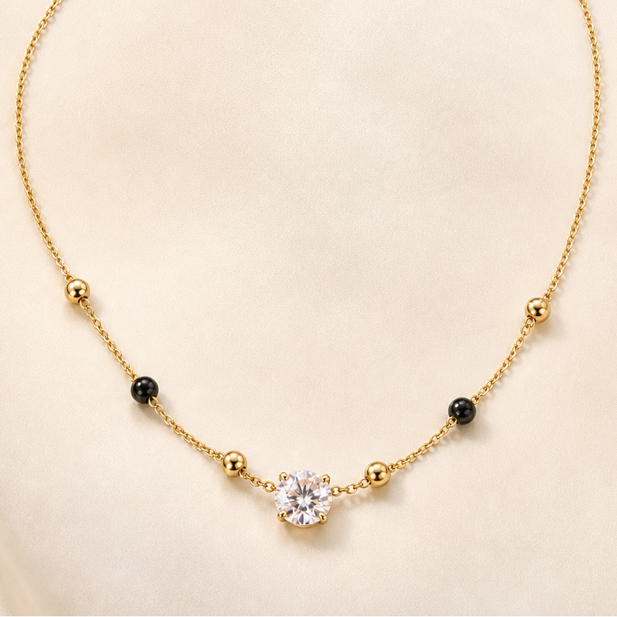 One necklace in yellow-gold-tone metal with a polished finish. It is a single strand of fine cable chain, with a short extender chain at the clasp end terminating in a small flat rectangular metal tag; the clasp is a lobster or spring-ring type, partly tangled and partly obscured.