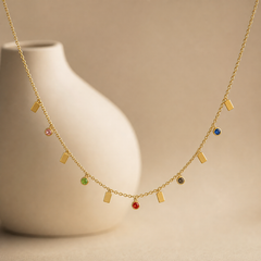 One single-strand station necklace in yellow-gold-toned metal with a polished finish, built as a fine-gauge cable chain carrying alternating dangling drops. The chain run spans roughly 60 times the width of the largest component; no extender is visible and the clasp is partly obscured at the rear, so its working type cannot be confirmed.