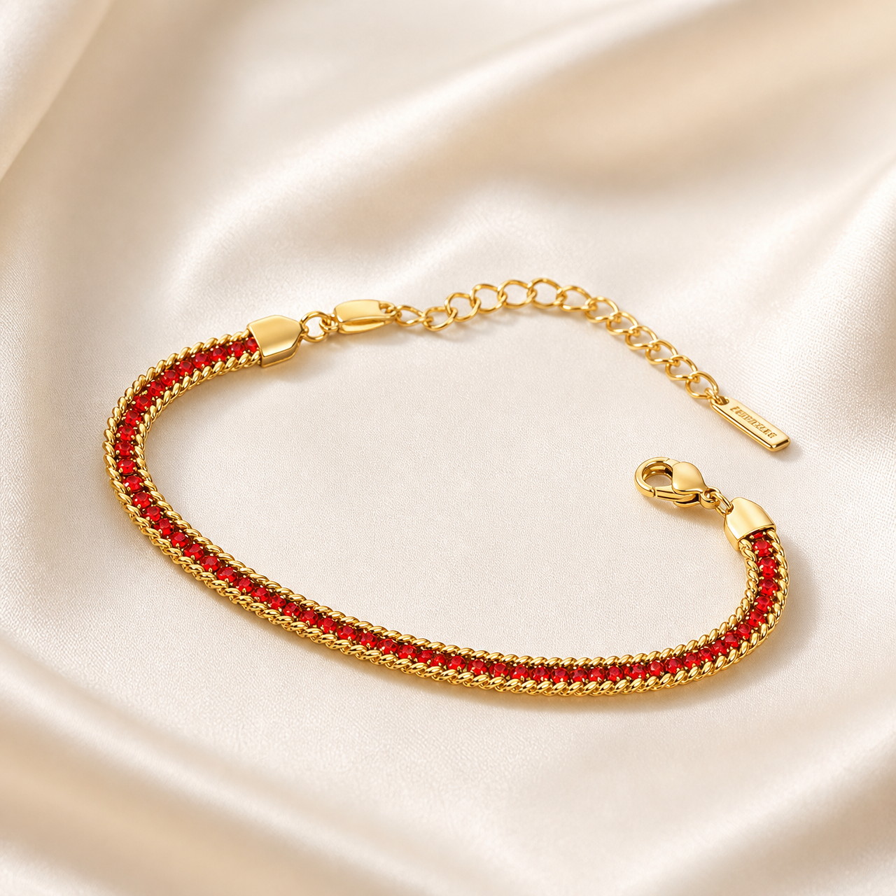 A single flexible bracelet in yellow-gold-toned metal with a polished finish. The main body is a flat, tightly woven herringbone-style chain of fine gauge, bordered on both long edges by a slightly raised twisted rope trim. Set continuously along the centre of the band is one unbroken row of small round faceted red stones, each held in an individual metal bezel or channel setting, the settings matching the gold tone of the chain; the row runs the full decorative length between two smooth, shield-shaped