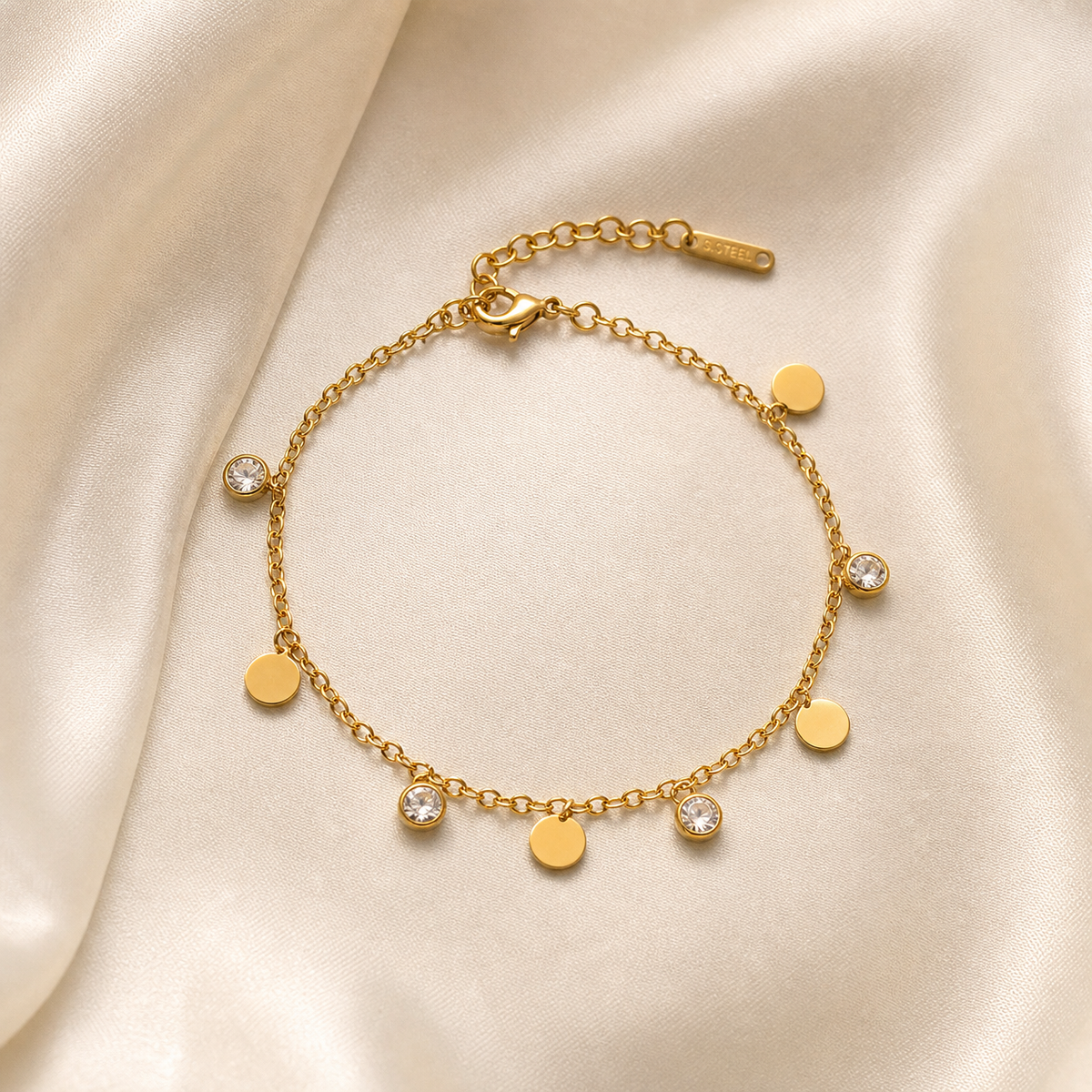 One wrist-worn chain bracelet in yellow-gold-toned metal with a polished finish. It is a single strand of fine, small-gauge oval cable chain, unbranched, carrying eight small dangling charms on individual jump rings spaced along the strand. The chain run is roughly 30 to 35 times the width of the largest component, and the extender is approximately one-fifth of the main chain length.