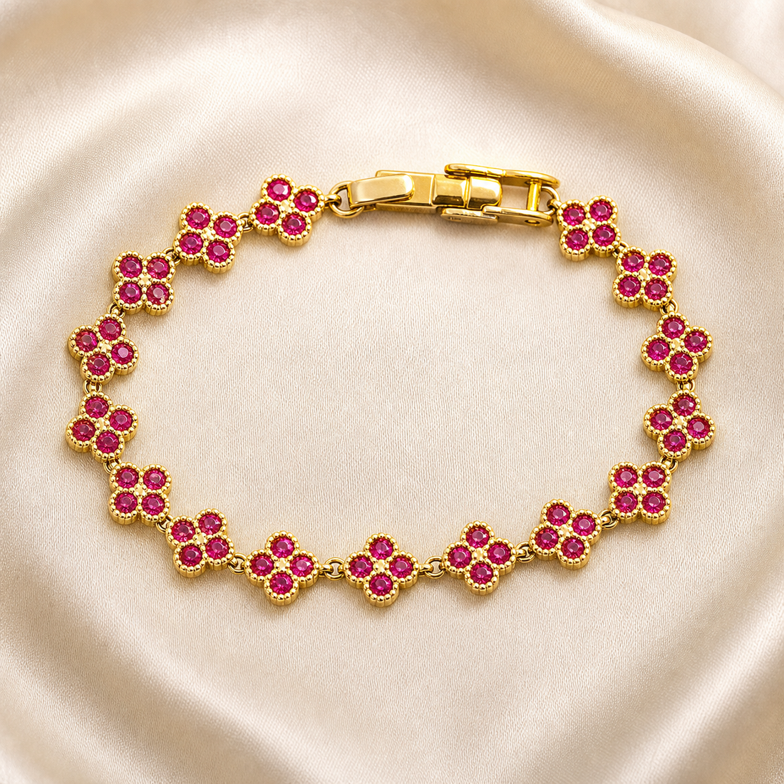 A single wrist-worn chain bracelet in yellow-gold-tone metal with a polished finish. Construction is a single flexible strand: a run of identical four-petal flower stations joined by small round connecting links of fine gauge, each flower formed of four round faceted pink-red stones in matching gold-tone petal-shaped settings, likely bezel or prong-set, with no dangling charms, beads or separate motifs.