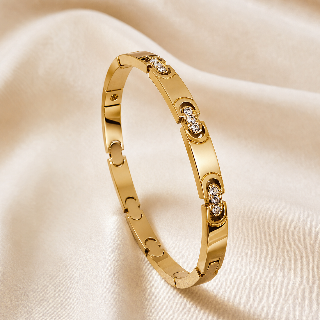 A single rigid bangle bracelet in polished yellow gold, formed as a narrow flat band of uniform width with a smooth, reflective finish. The band is pierced at intervals with openwork motifs: alternating plain cut-out shapes resembling small arches and keyhole-like silhouettes, and raised ornamental stations each set with small clear faceted elements clustered within shaped metal borders; these stone-set stations appear in slightly different forms, one a compact oval cluster and others elongated multi-stone