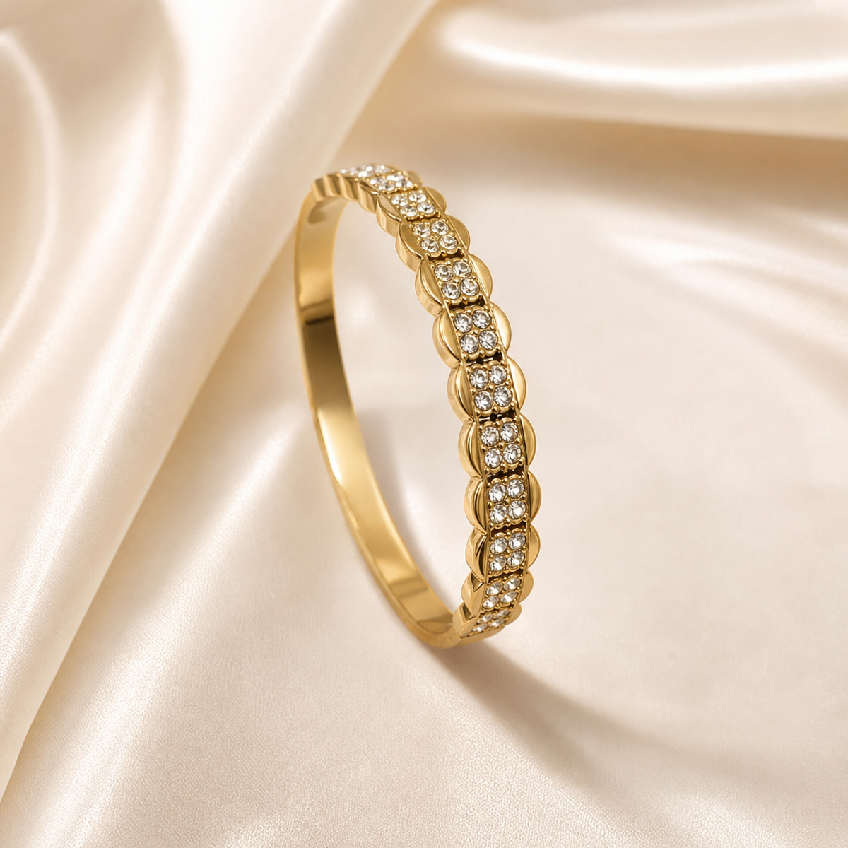 A single rigid bangle bracelet in yellow-gold-coloured metal with a high-polish finish. The band is of even width throughout: one half is a smooth plain polished band with a gently curved outer surface, while the opposite half is decorated with a repeating sequence of raised, rounded petal or leaf-shaped solid-gold links alternating with recessed rectangular pavé panels.