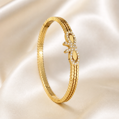 A single rigid bangle in polished yellow gold with a bright reflective finish. The band is a solid, slim circular form built from two to three closely joined parallel ridges, its outer surface edged with a fine reeded or fluted texture running continuously around the circumference.