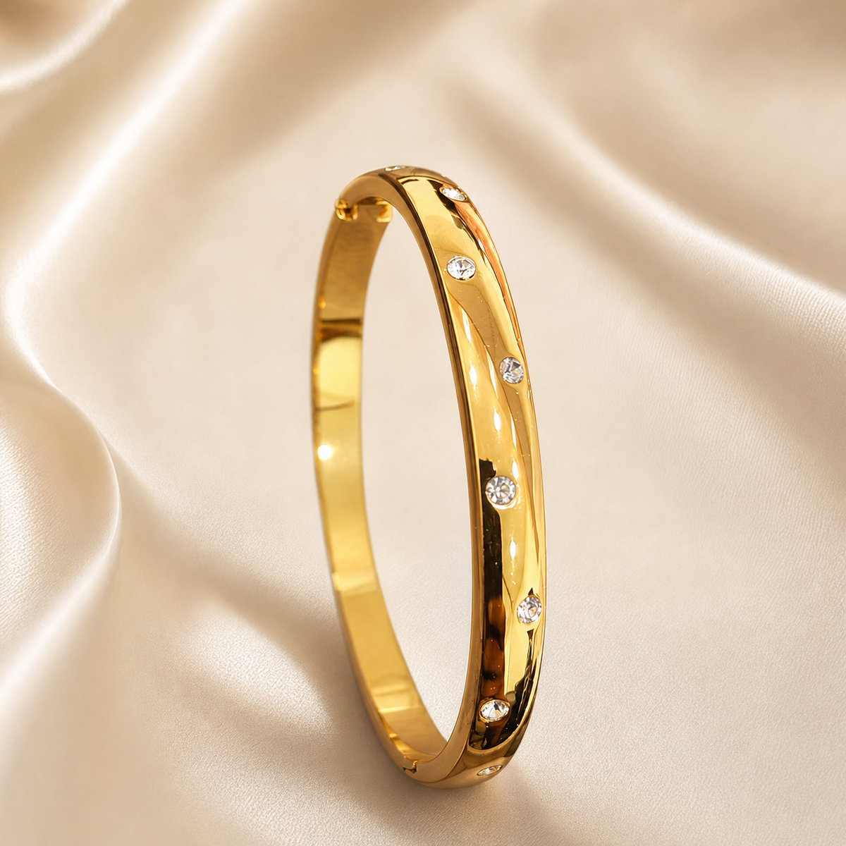 A single rigid oval bangle of yellow gold with a high-polish mirror finish, formed as a continuous solid band of medium gauge with a softly domed outer profile and flat inner surface. Set into the outer face are round, clear, colourless faceted stones in flush (gypsy) settings, each sitting level with the metal surface in its own small circular seat; the stones are of similar small size and are distributed at irregular, uneven intervals around the visible face rather than in an even grid, with some