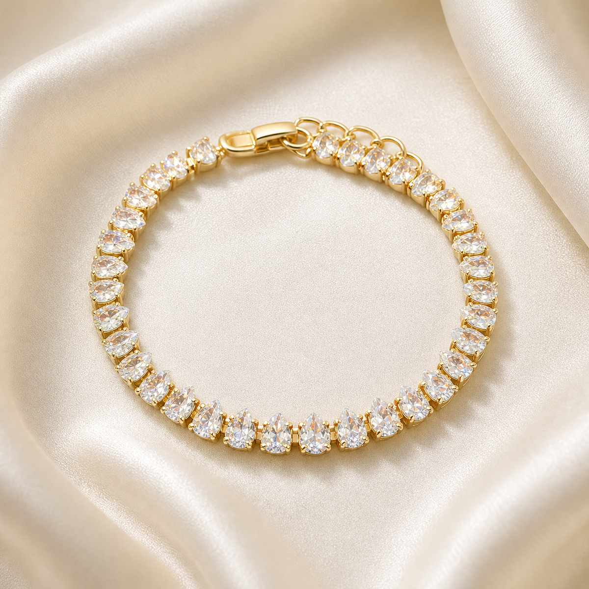 One wrist-worn chain bracelet. Yellow-gold-tone metal with a polished finish. Construction is a single flexible stone-set strand: fine-gauge articulated tennis-style links connect individual basket settings end to end, with no branches. The stone-set run is approximately 30–35 times the width of the largest pear element; the short plain terminal/adjuster section is about one-twentieth of the main run.