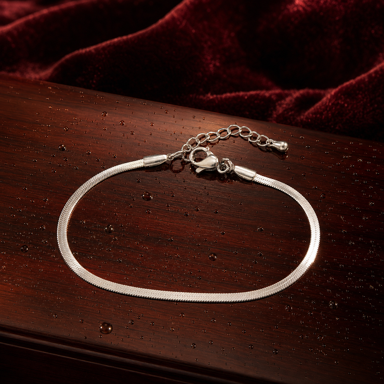 One chain bracelet in silver-tone metal with a bright polished finish. Construction is a single continuous strand of flat, flexible snake (herringbone-style) chain of narrow, uniform gauge, with no branches, joins or secondary strands along its run. The largest component is the lobster clasp; the main chain run is approximately 45 to 50 times the clasp's width.