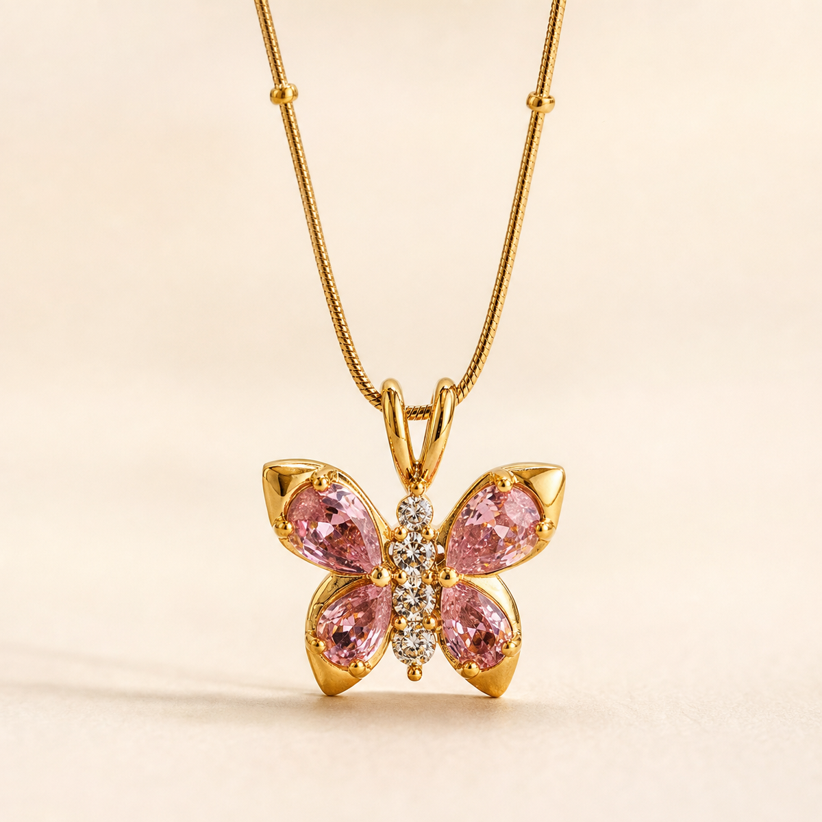 Gold-tone 304 stainless steel butterfly pendant necklace with four pink teardrop stones and a column of clear stones on a snake chain