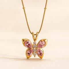 No earrings are present in this image. The visible product is a single pendant necklace: a yellow-gold-tone fine snake chain with small spaced bead stations, suspending a butterfly-shaped pendant through a double-loop bail. The pendant has polished gold-tone metal with four pear-cut pink faceted stones forming the wings in prong settings, and a vertical body of small round clear faceted stones. Pendant drop is roughly one and a half times its widest span.