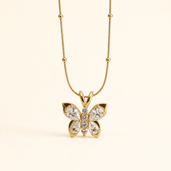 The photograph contains no earrings; the product shown is a single pendant necklace, reported here only because it is the sole visible jewellery piece. It has a yellow-gold polished snake chain fitted with evenly spaced small round metal beads, suspending one solid-metal butterfly pendant.