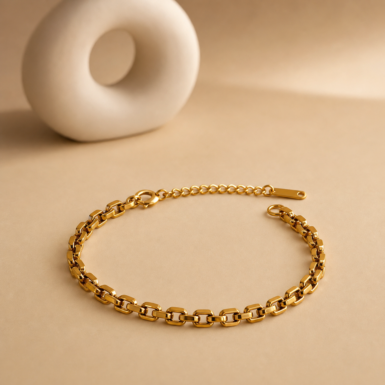 One wrist-worn chain bracelet in a warm yellow-gold-toned metal with a polished, reflective finish. It is a single continuous strand of medium-gauge rectangular brick-link (panther-style) chain, each link a flat rounded-corner bar segment articulated to the next, with no branches, charms, stations, beads or stones anywhere along the run. The main chain run measures approximately 25 to 30 times the width of one link.