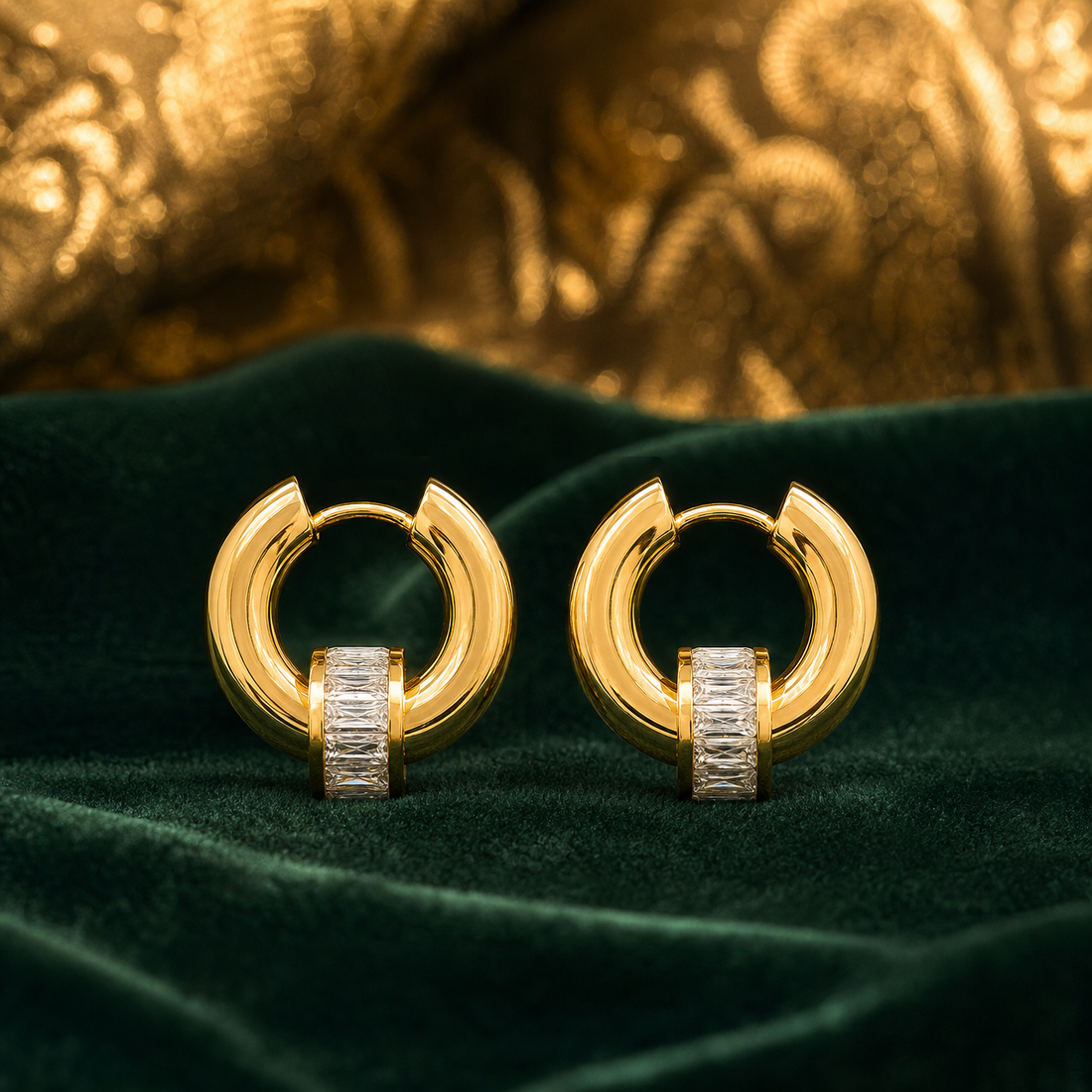 Two ear-worn huggie hoop earrings of matching design, in polished yellow gold with a high-shine finish. Each is a small hinged hoop with a huggie hinge closure; the hoop is chunky and rounded in profile, and the overall drop is roughly one and a half times the hoop's width. Threaded onto each hoop is a single cylindrical barrel element channel-set with a row of clear rectangular baguette-cut faceted stones, free to slide along the hoop rather than fixed.