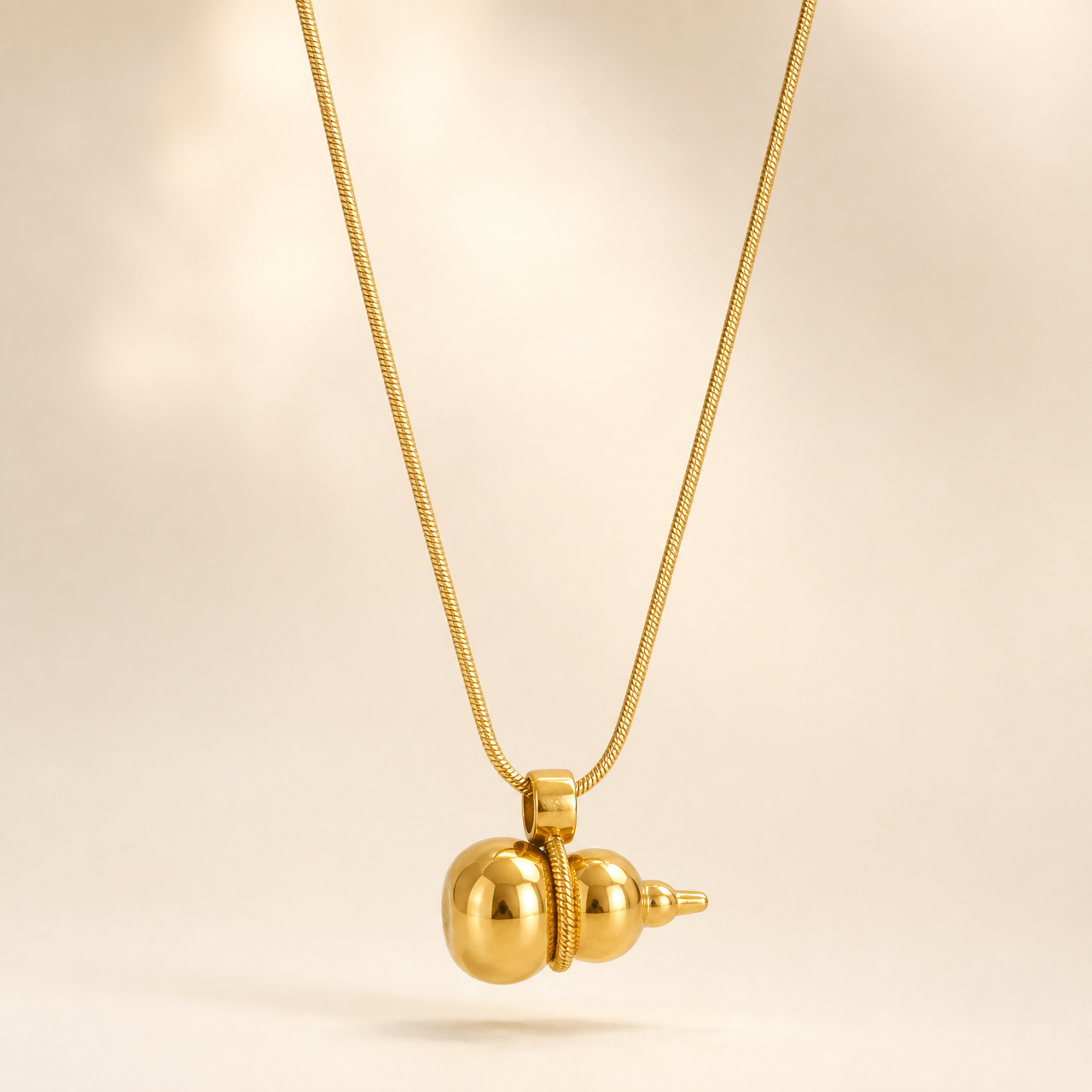 One necklace in polished yellow-gold-tone metal with a high-shine finish. It is built on a single fine snake chain of narrow, tight gauge forming one continuous strand; the clasp end is not visible in the frame, so no closure, extender or terminal tag can be confirmed, and no extender chain is seen. The visible chain run measures roughly twenty to twenty-five times the width of the largest component.