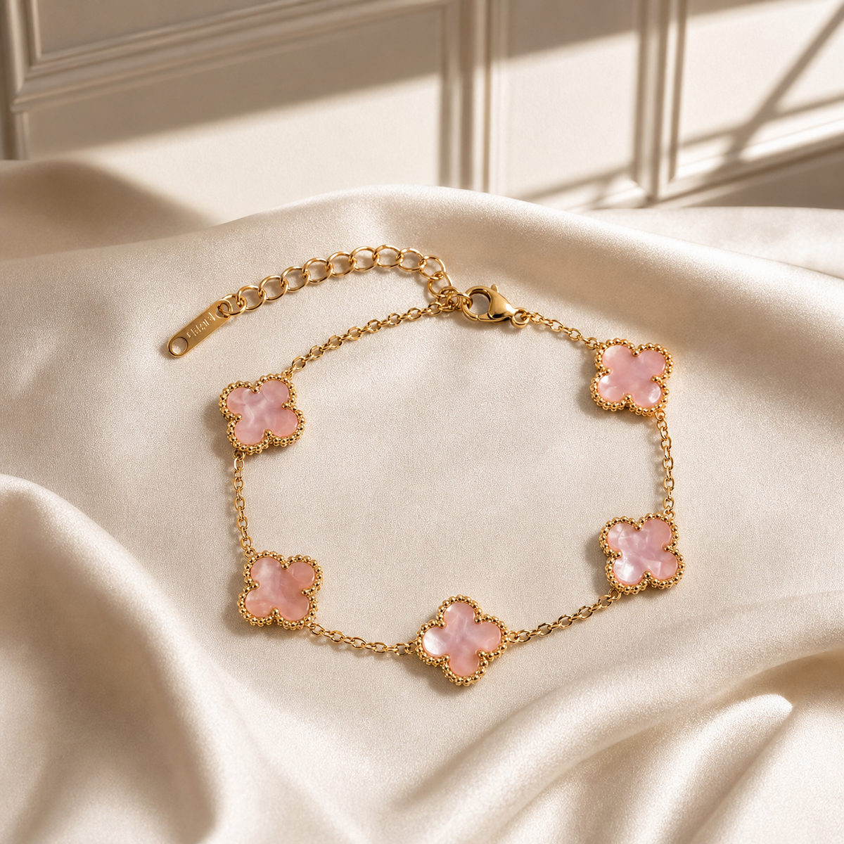 One chain bracelet in yellow-gold-tone metal with a polished finish, built as a single strand of fine cable chain in a small oval-link gauge, punctuated by five four-lobed clover (quatrefoil) motifs as inline stations. The chain run is approximately 13 times the width of the largest motif, and the extender is roughly one third of the main chain length. A working lobster-claw clasp is visible at one end.