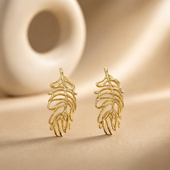The photograph contains not a kada or bangle but a matched pair of two rigid gold-toned metal ear ornaments, each an openwork feather or leaf motif; no circular band, closure, hinge, gap, terminals or wrist-worn form is present, so band width, cross-section and closure type cannot be reported.