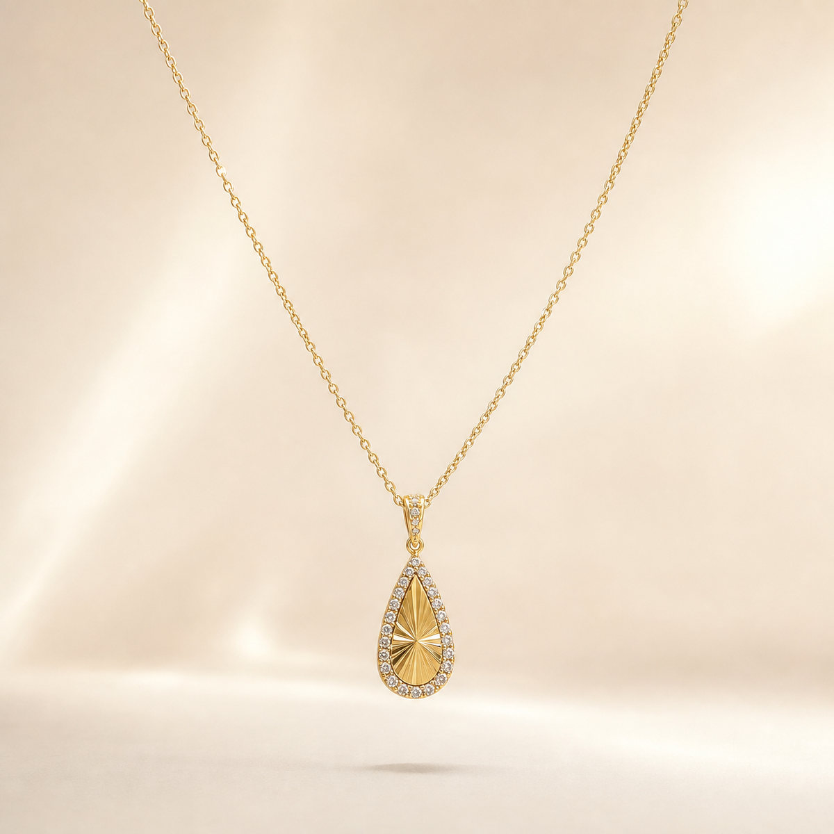 One necklace with a single dominant pendant, in yellow-gold-tone metal with a polished finish. The piece is a single fine-gauge cable chain of small oval links, unbranched, running in one continuous strand from the clasp region to the pendant bail; the chain run is approximately 30 times the width of the pendant. No extender chain is visible, so no extender fraction can be stated. The working closure is not visible; the chain is partly obscured where it passes out of view at the back.