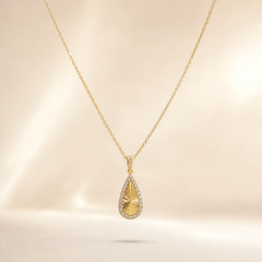 One necklace with a single dominant pendant, in yellow-gold-tone metal with a polished finish. The piece is a single fine-gauge cable chain of small oval links, unbranched, running in one continuous strand from the clasp region to the pendant bail; the chain run is approximately 30 times the width of the pendant. No extender chain is visible, so no extender fraction can be stated. The working closure is not visible; the chain is partly obscured where it passes out of view at the back.
