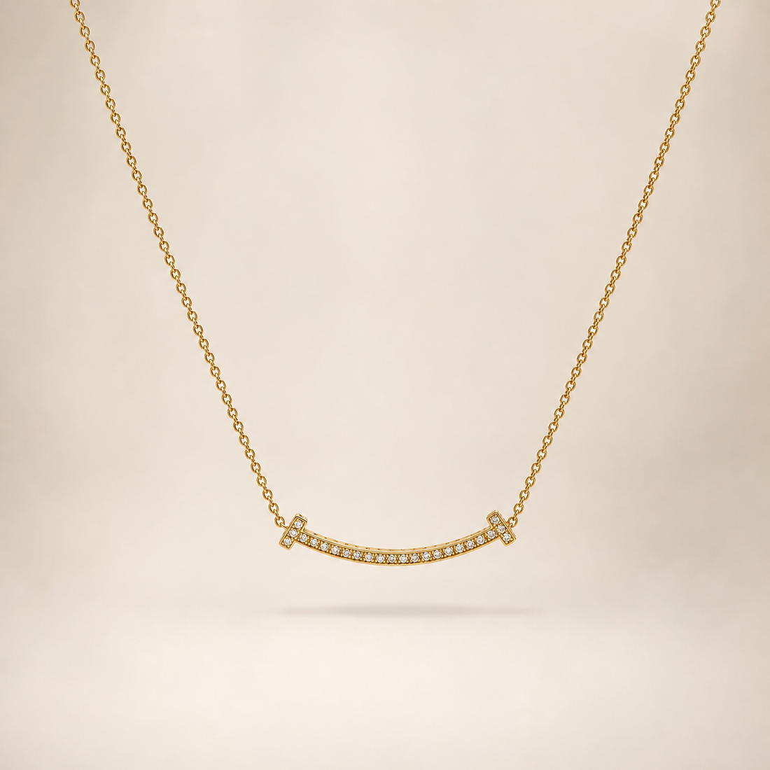 One necklace in yellow-gold-tone metal with a polished finish. It is a single strand of fine, small-gauge cable chain running continuously from a clasp at one end around to the far end; the chain run is approximately 10 to 12 times the width of the largest component, the central curved bar. No extender chain is visible, so no extender-to-main-chain fraction can be stated; a working clasp is present but its mechanism is partly obscured at the rear of the strand.