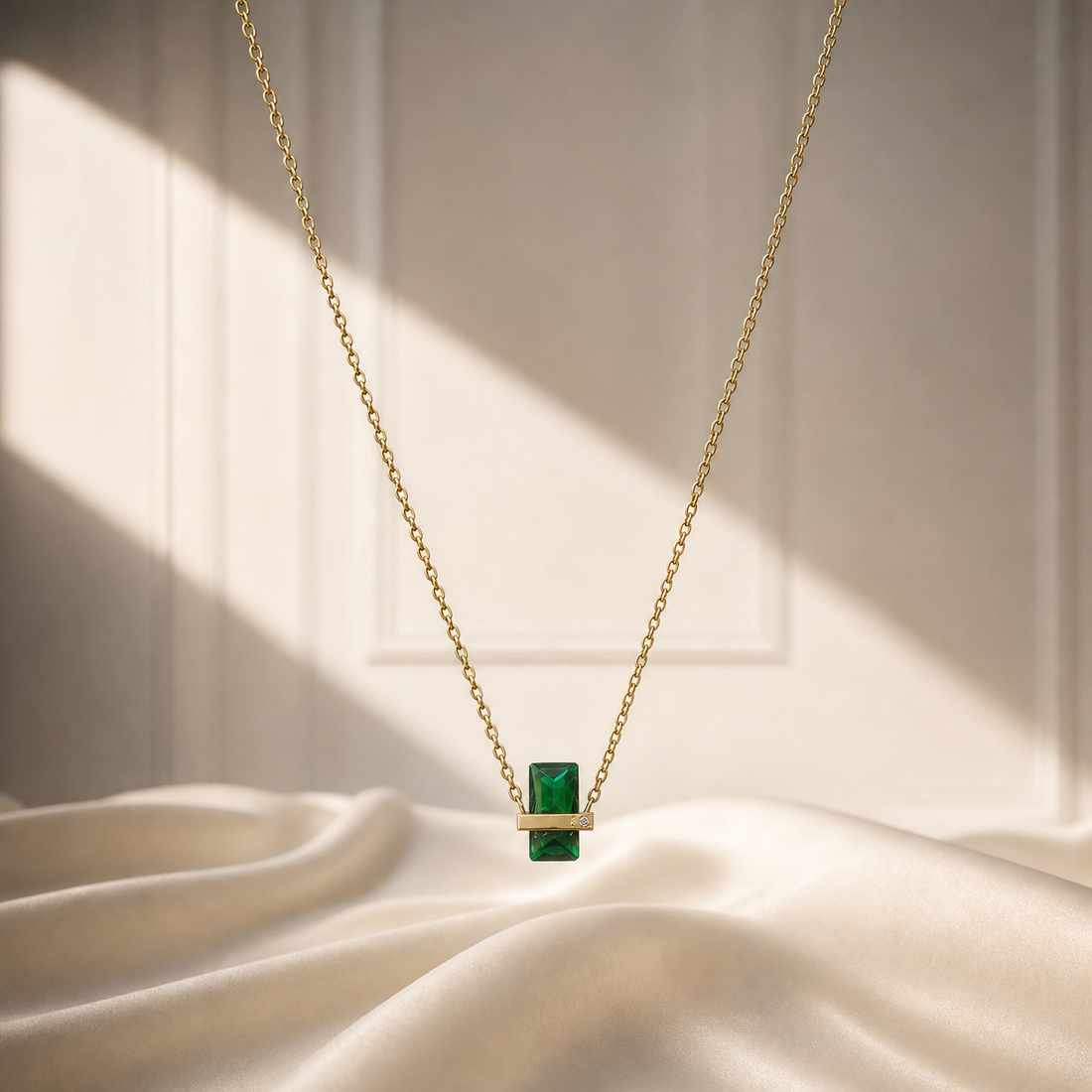 One necklace in yellow-gold-coloured metal with a polished finish, formed as a single fine cable chain of small round links, roughly 1mm gauge. The chain run is approximately 40 times the width of its largest component. No working closure, clasp, extender or terminal tag is visible; the chain ends are out of view and partly obscured. The strand carries a single dominant fixed pendant with no other stations, beads or charms along the run.