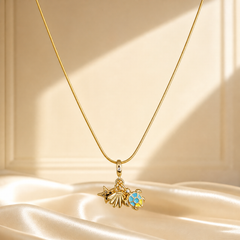 One necklace in yellow-gold-tone metal with a polished finish, built as a single fine snake chain of very small, tight links. The chain run is approximately 25 times the width of the largest pendant component. No clasp, extender or terminal tag is visible, so closure type cannot be confirmed. At the chain's centre hangs a charm-cluster pendant on a plain tapered bail set with one tiny round clear faceted element.