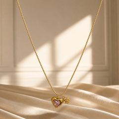 One necklace in yellow-gold-toned metal with a polished finish. It is a single strand of fine, tight woven foxtail-style chain of small gauge, its total run roughly 30 to 35 times the width of the largest component, the heart pendant; no extender chain is visible. The clasp is not visible in the image and the rear of the strand is partly obscured.