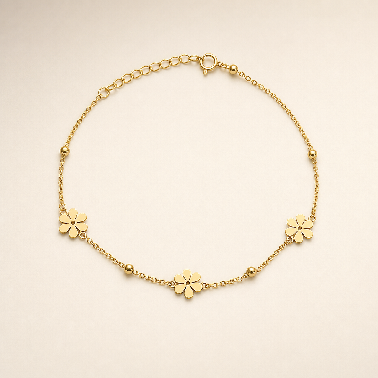 One anklet in yellow-gold-toned metal with a polished finish. Construction is a single strand of fine cable chain in small oval links, with no branches; the full chain run is roughly twenty times the width of the largest component, and the extender, a short section of larger open oval links terminating at the clasp, is about one fifth of the main chain length. A working spring-ring clasp is visible connecting to the extender.