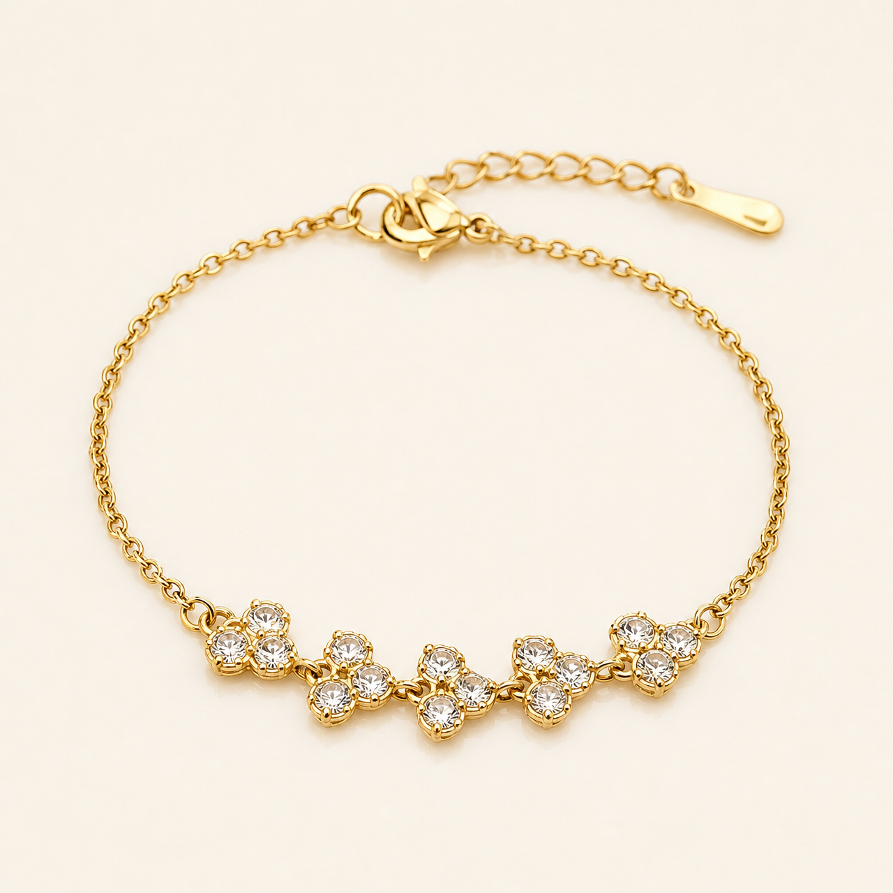 One wrist-worn chain bracelet in yellow-gold-toned metal with a polished finish. Single-strand fine cable chain of small-gauge oval links, with one lobster-claw clasp at one end and an extender chain of larger curb links terminating in a single elongated teardrop-shaped metal tag at the other; a working closure is visible. The full chain run is roughly fifteen times the width of the largest component, and the extender is about one quarter of the main chain length.