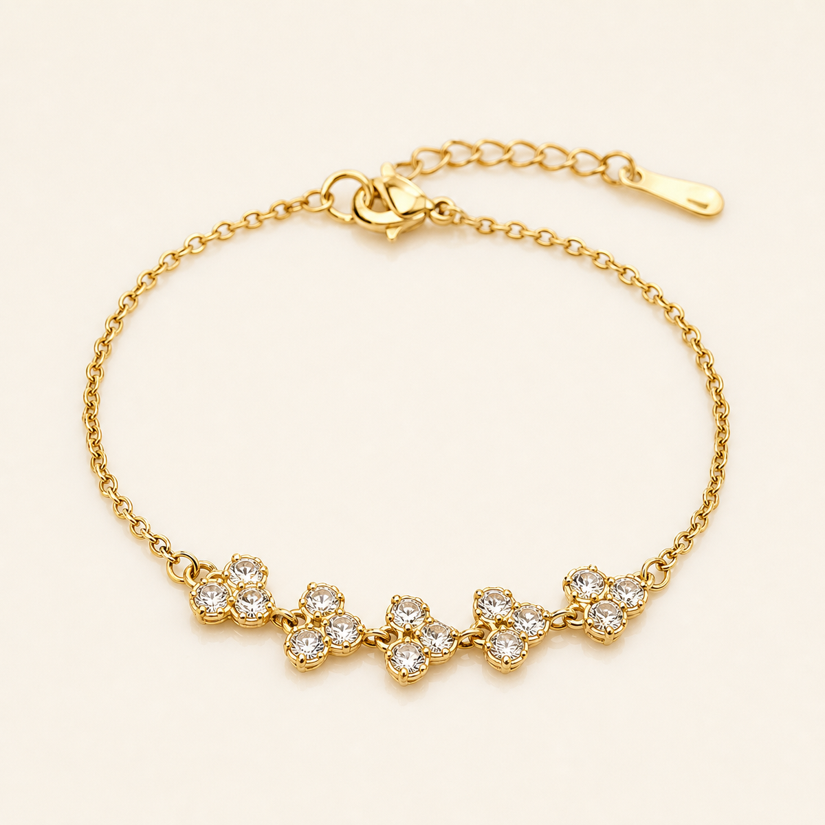 One wrist-worn chain bracelet in yellow-gold-toned metal with a polished finish. Single-strand fine cable chain of small-gauge oval links, with one lobster-claw clasp at one end and an extender chain of larger curb links terminating in a single elongated teardrop-shaped metal tag at the other; a working closure is visible. The full chain run is roughly fifteen times the width of the largest component, and the extender is about one quarter of the main chain length.