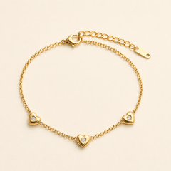 One anklet in yellow-gold-toned metal with a polished finish. It is a single-strand fine cable chain of small round links. A working lobster clasp is visible at one end, joined to an extender of larger open oval links roughly one quarter the length of the main chain, terminated by one elongated flat drilled tag. The main chain run is approximately twenty-five times the width of the largest component.