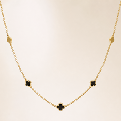 Single station necklace of yellow-gold tone with a polished finish, built as one fine cable chain of small oval links carrying fixed four-leaf clover (quatrefoil) motifs threaded directly onto the chain run rather than dangling. The chain run is approximately 60 times the width of the largest clover motif; no extender chain is visible in the field and the closure is partly obscured, with no working clasp clearly resolvable.