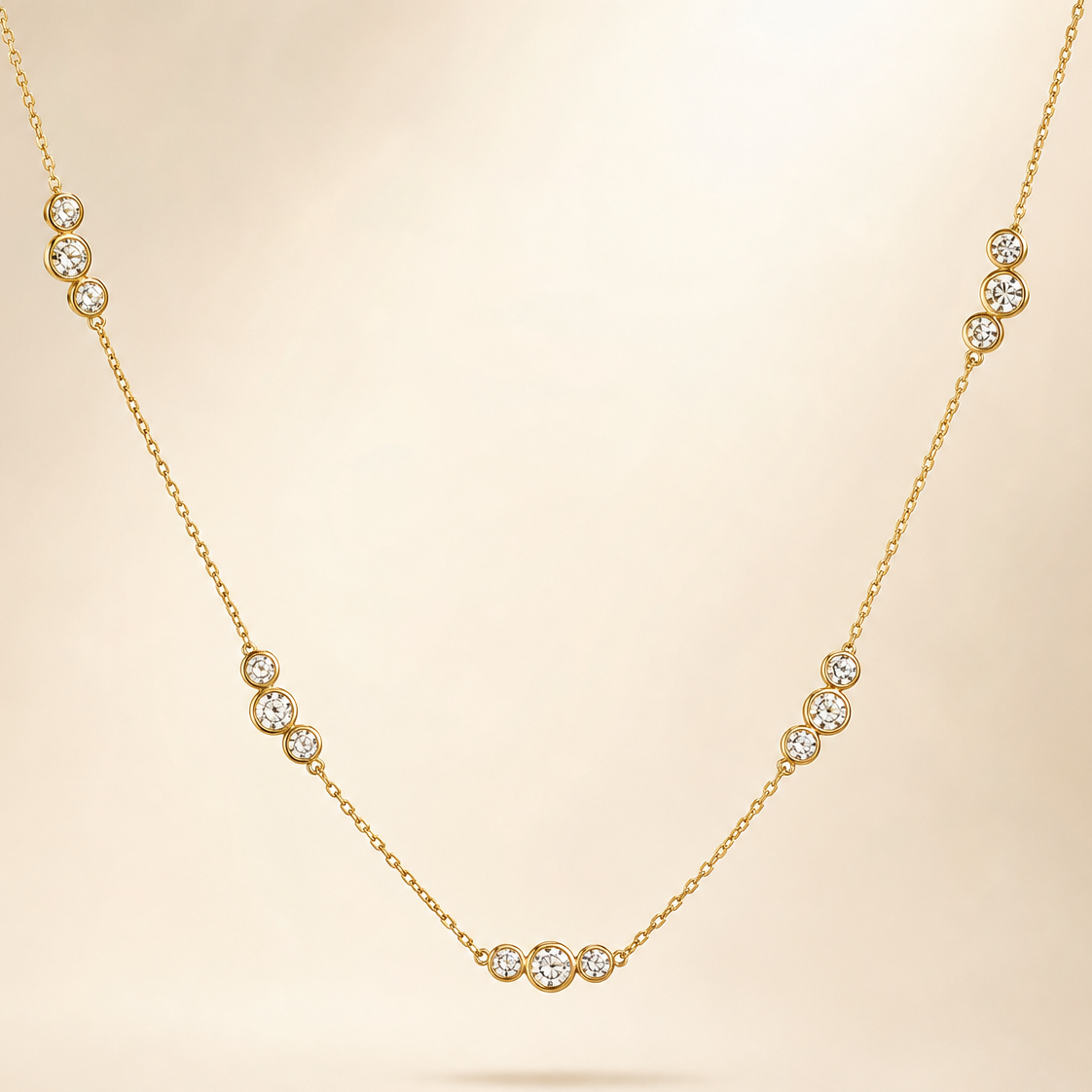 One single-strand station necklace in yellow-gold-toned metal with a polished finish. The chain is a fine cable link of small gauge, carrying five fixed station clusters spaced along the strand; each cluster comprises three round clear faceted stones in rub-over bezel settings, the bezels touching so each trio reads as one connected bar-like unit, with the middle stone of some clusters sitting slightly larger than its neighbours.