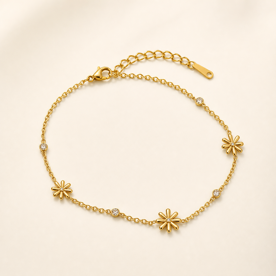 One anklet. Yellow-gold-tone metal with a polished finish. A single-strand fine cable chain of small oval links carries distributed stations along its full length and is fitted with one lobster clasp plus one adjustable extender chain of larger cable links ending in one flat elongated pierced terminal tag; the closure is visibly workable.
