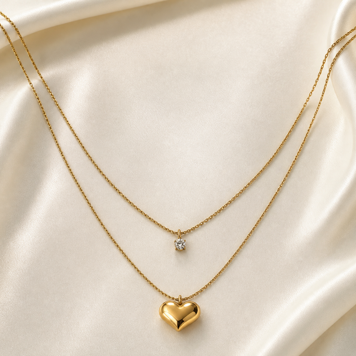 A two-strand layered pendant necklace in yellow-gold-coloured metal with a polished, reflective finish. Both strands are fine twisted rope-style chains of similar gauge, running roughly parallel and diverging only in length. The shorter, inner strand carries one pendant: a single round clear faceted stone, approximately 4 to 5 mm, held in a multi-prong setting suspended from a small jump-ring bail at the chain's centre.
