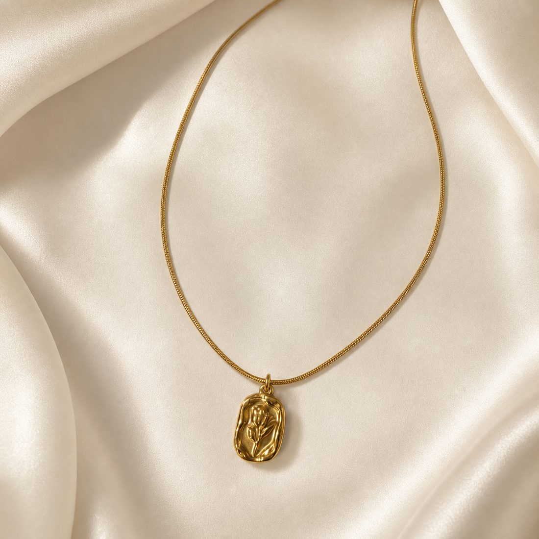 One necklace comprising a single strand of yellow-gold-coloured snake chain of fine gauge with a smooth, polished finish, suspended in a narrow U-shape with both upper ends running out of frame. Tracing from either end toward the centre, the chain is continuous and undecorated until the bottom centre, where one pendant hangs.