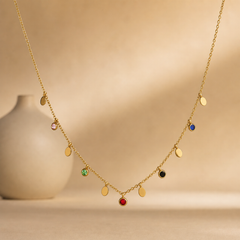 A single necklace in yellow-gold-coloured metal with a polished finish, built as one fine cable chain of small gauge links carrying alternating dangling charms. The chain run is approximately 40 times the width of the largest component, the red bezel-set stone; no extender is visible and the clasp is not visible, the chain ends running out of view, so closure type cannot be confirmed.