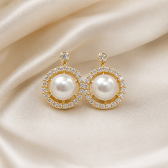 A matched pair of two earrings in yellow-gold-toned metal with a polished finish. Each earring is a fixed circular cluster suspended from a short post: at the top of each is a small round clear faceted stone in a bezel or rim setting, joined by a slim metal link to the main round head below.