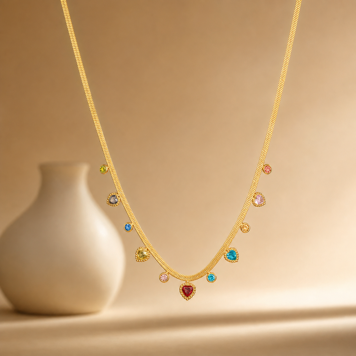 One necklace, gold-tone metal with a polished finish, built as a single flat herringbone chain of fine, tightly woven links. The chain run is approximately 30 times the width of the largest charm; no extender chain is present, and no working clasp is visible in the view. Eleven bezel-set dangling charms hang from the chain at uneven intervals, each mounted through a small fixed bale so it swings below the strand.