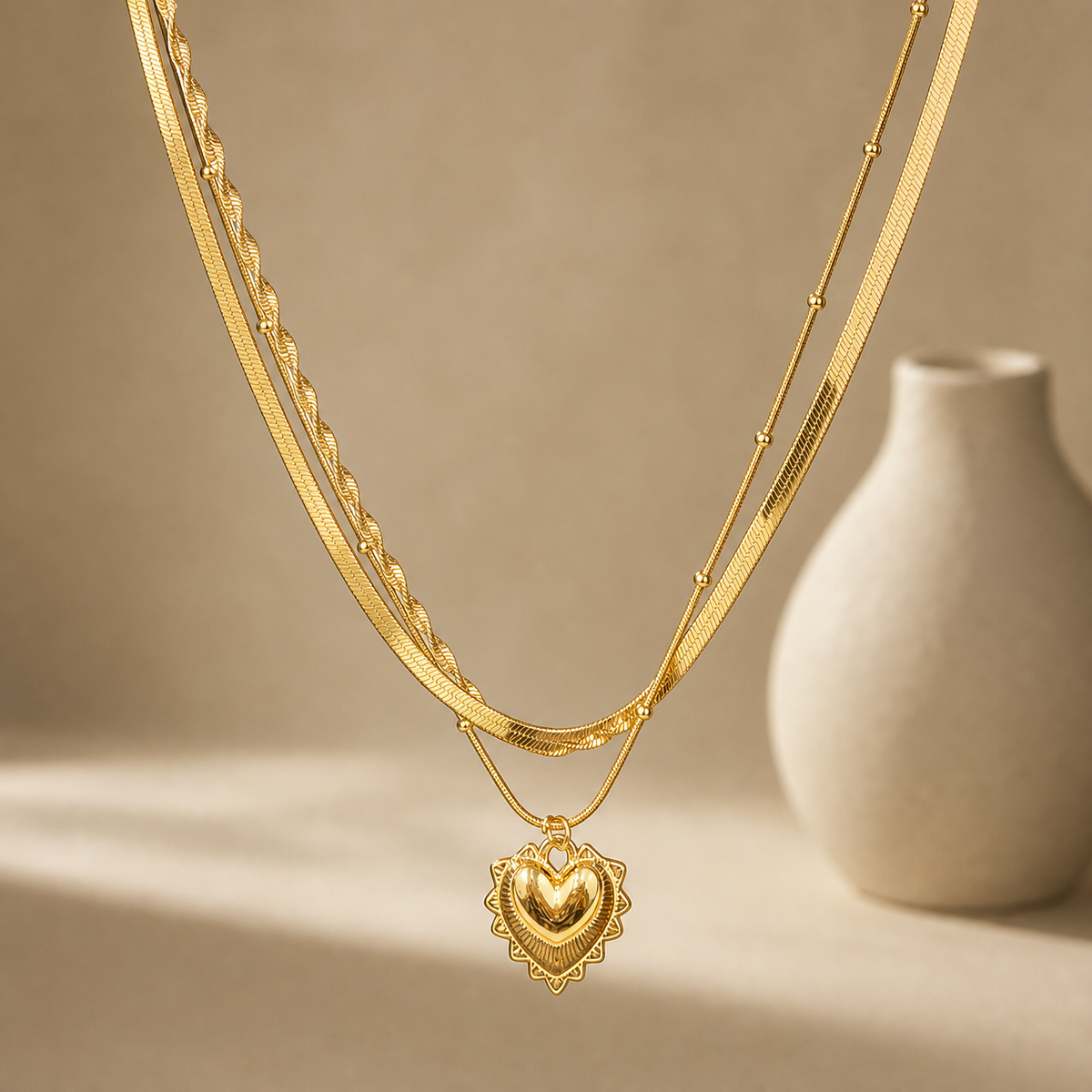One necklace in yellow-gold-toned polished metal, built as three joined parallel strands sharing common end connections. The strands are: a wide flat herringbone chain; a fine snake chain punctuated by small round ball stations spaced irregularly along its run; and a second fine snake chain, set at a slightly longer drop, that carries the pendant. The longest chain run measures roughly 30 times the pendant's width; no extender chain is visible.