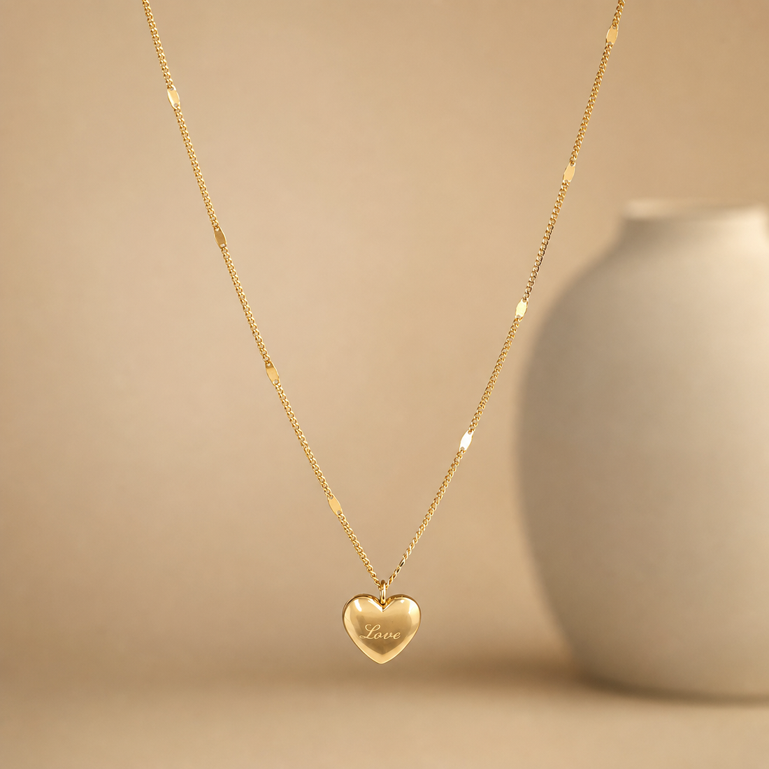 A single yellow-gold necklace with a polished finish, built from one fine cable chain of small oval links. Spaced along the strand are small solid-metal bar or oval stations integrated into the chain, appearing on both sides of the run at uneven intervals; their exact total is not confidently resolvable. The chain run is approximately 22 to 26 times the width of the largest component, the central heart pendant, consistent with a mid-length necklace.