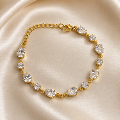 One chain bracelet in yellow-gold-tone metal with a bright polished finish. Single-strand construction: a short run of small round cable chain links forms an extender at one end, meeting a lobster clasp with a flat rectangular metal terminal tag; the clasp connects to the gem-set main run. The chain run measures roughly twenty times the width of the largest component, and the extender chain is about one quarter of the main run's length; a working lobster closure is visible.