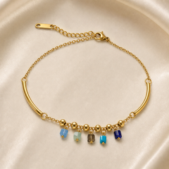 One anklet, gold-tone metal with a polished finish. It is a single fine-gauge cable chain whose run is interrupted by two long curved hollow tube segments joined to the chain by jump rings. Total chain run is roughly 25 times the width of the largest component (the tube bars), and the curb-link extender is about one quarter of the main chain length. A working lobster clasp is visible, connecting to the extender chain, which ends in one flat elongated terminal tag.