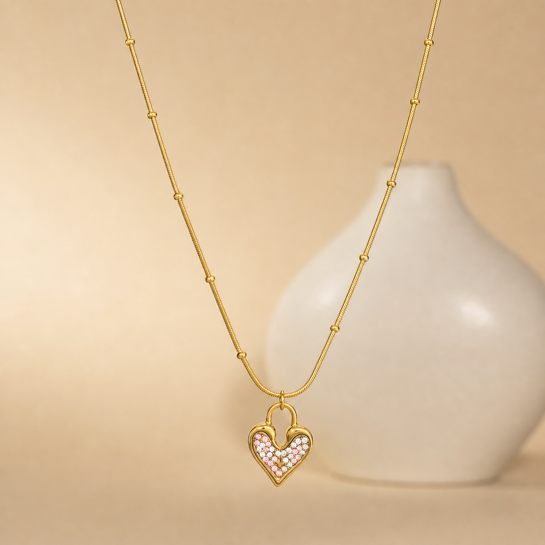 One necklace in yellow-gold-tone metal with a polished finish. It is a single strand of fine, round snake chain of slim gauge, fitted at intervals with small round gold bead stations threaded directly onto the chain; counting from the clasp end toward the pendant, the beads are spaced irregularly along the strand rather than symmetrically, with roughly four to five visible on each side at uneven gaps.
