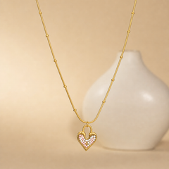 One necklace in yellow-gold-tone metal with a polished finish. It is a single strand of fine, round snake chain of slim gauge, fitted at intervals with small round gold bead stations threaded directly onto the chain; counting from the clasp end toward the pendant, the beads are spaced irregularly along the strand rather than symmetrically, with roughly four to five visible on each side at uneven gaps.