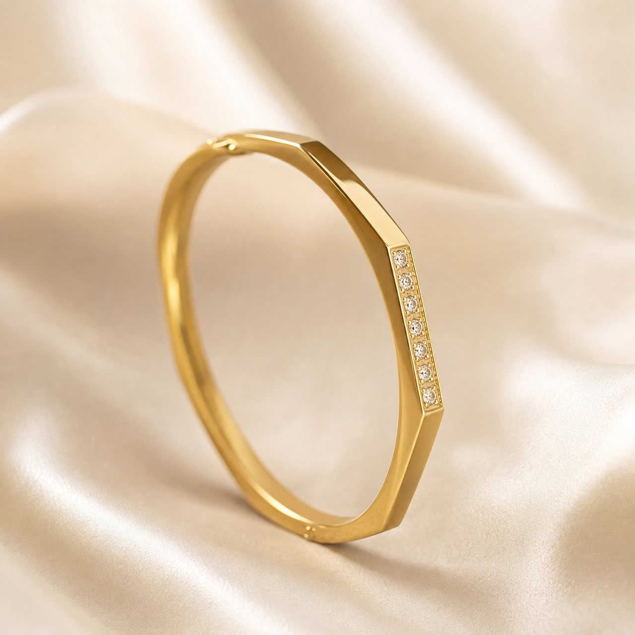A single rigid bangle (kada) in yellow gold with a polished finish. The band is a continuous closed ring of medium gauge with an angular, faceted outer profile: broad flat bevels run along the band, giving a slightly hexagonal cross-section rather than a round one.
