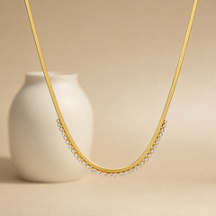 A single gold-tone necklace, quantity one, in yellow-gold metal with a polished finish. It is built as one flat, flexible snake or herringbone chain of fine gauge, forming a single continuous strand with no branches. The chain run is approximately 60 times the width of the largest stone component; no extender chain is visible, and no working closure is visible from this side.