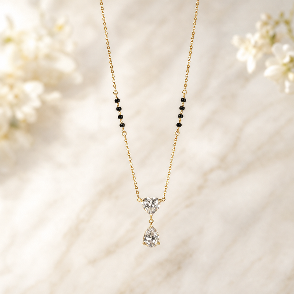 One necklace in yellow-gold-tone metal with a polished finish, built as a single strand of fine curb chain of small, uniform link gauge. Each side of the strand carries a station group of four small cylindrical black beads threaded onto the chain between chain-link spacers, giving eight black beads in total, symmetrically placed partway along the strand. The chain run is approximately twenty-five to thirty times the width of the largest component, the central stone.